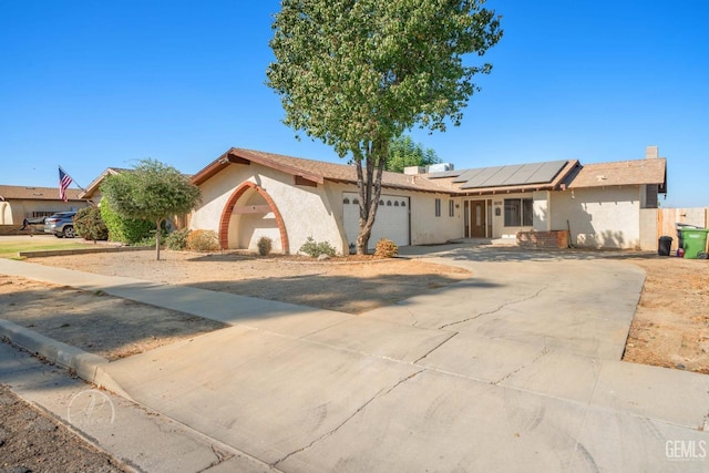 single story home with a garage and solar panels