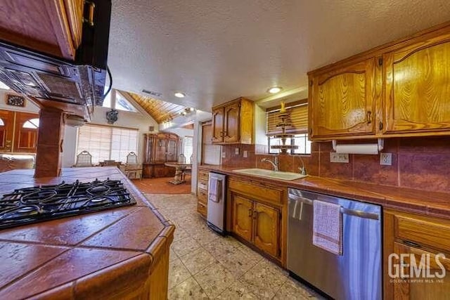 kitchen with a wealth of natural light, a sink, brown cabinetry, dishwasher, and tile counters