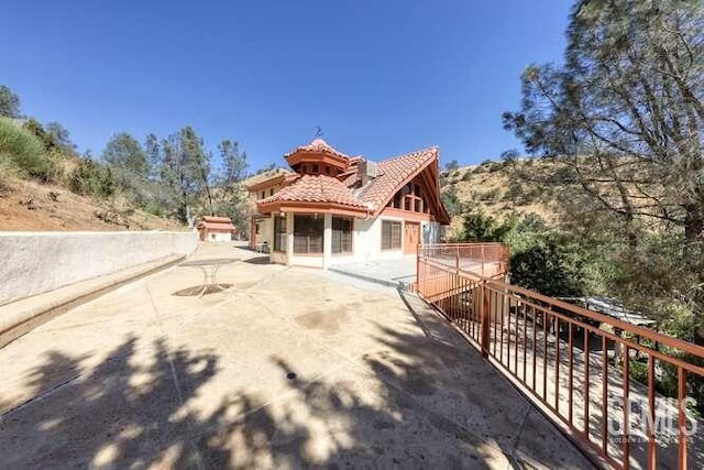 back of property with stucco siding, a patio, and a tile roof