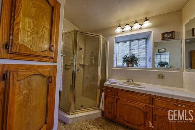 full bathroom featuring backsplash, a textured ceiling, a stall shower, and vanity