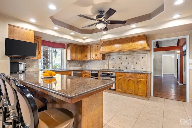 7858 Stine Rd, Bakersfield, CA 93313 - kitchen featuring brown cabinetry, premium range hood, appliances with stainless steel finishes, and a peninsula