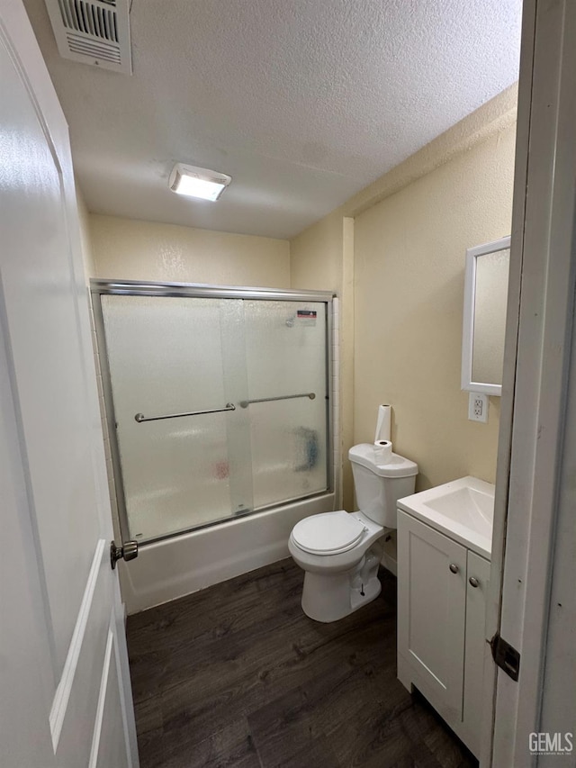 bathroom featuring vanity, toilet, enclosed tub / shower combo, a textured ceiling, and wood finished floors