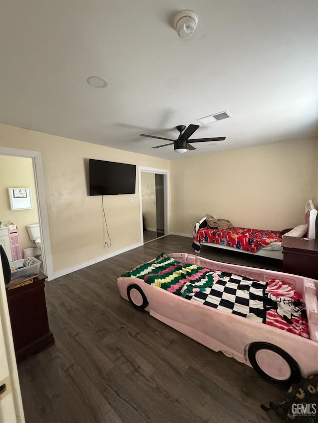 bedroom featuring independent washer and dryer, ceiling fan, dark wood-type flooring, visible vents, and baseboards