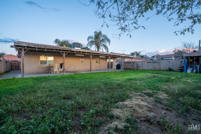 rear view of house with stucco siding, cooling unit, a lawn, a fenced backyard, and a patio