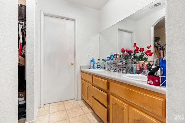 full bath with double vanity, visible vents, a spacious closet, and a sink