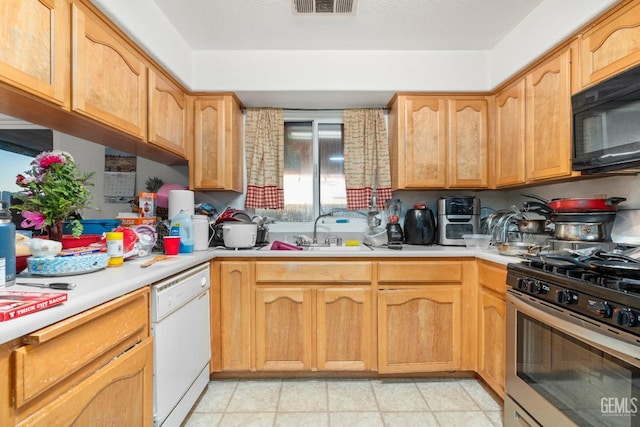 kitchen featuring black microwave, gas range, light countertops, white dishwasher, and a sink