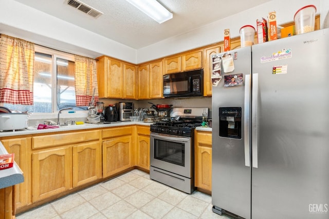 kitchen featuring visible vents, light countertops, stainless steel appliances, a textured ceiling, and a sink