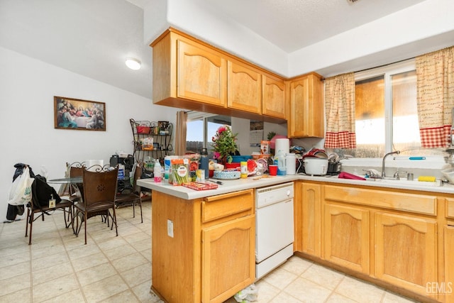 kitchen with a sink, a peninsula, light countertops, light floors, and dishwasher