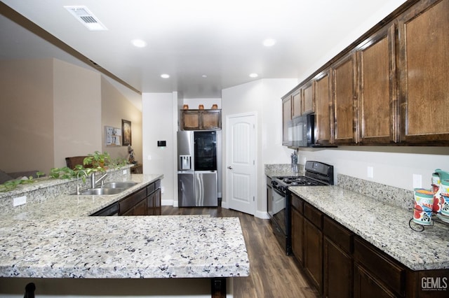 kitchen featuring light stone countertops, dark hardwood / wood-style flooring, dark brown cabinetry, sink, and black appliances