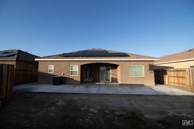 back of property with solar panels, cooling unit, and a patio