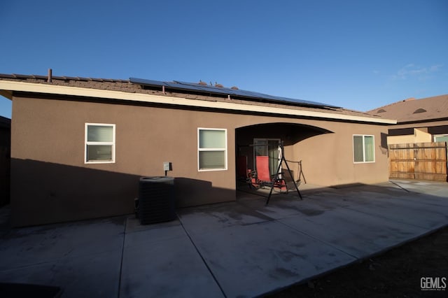 back of property with solar panels, central AC unit, and a patio area