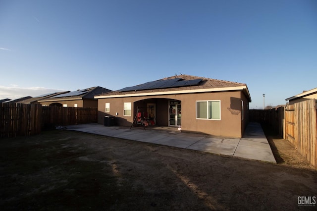 rear view of house with solar panels and a patio area