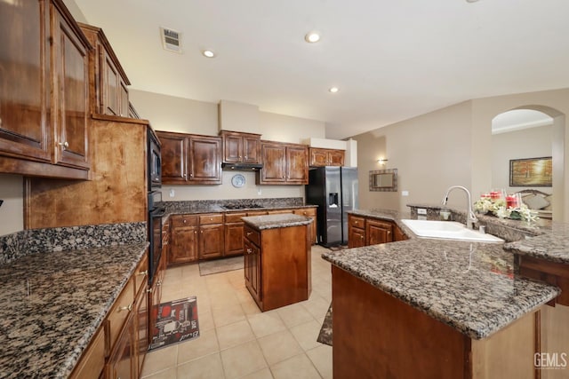 12504 Crown Crest Dr, Bakersfield, CA 93311 - kitchen with appliances with stainless steel finishes, a spacious island, arched walkways, light tile patterned floors, and dark stone countertops