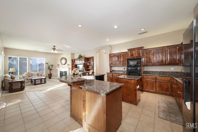 12504 Crown Crest Dr, Bakersfield, CA 93311 - kitchen with an island with sink, black appliances, light tile patterned flooring, arched walkways, and ceiling fan