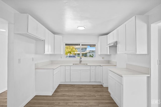 kitchen with hardwood / wood-style floors, white cabinetry, and sink