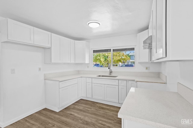 kitchen with hardwood / wood-style flooring, white cabinetry, and sink