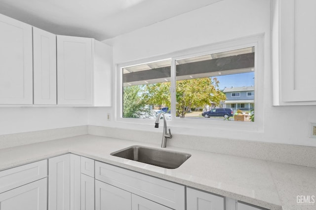 kitchen featuring white cabinetry, sink, and light stone countertops