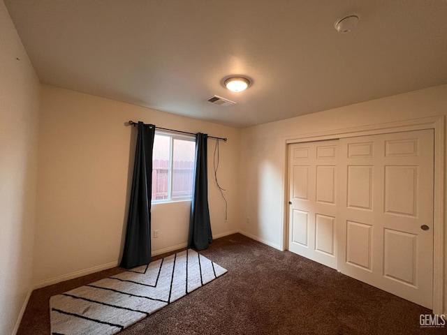 unfurnished bedroom featuring a closet and dark carpet