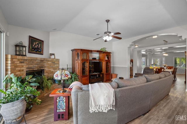 5512 Sicily Ct, Bakersfield, CA 93308 - living room featuring ceiling fan, wood finished floors, arched walkways, vaulted ceiling, and a brick fireplace