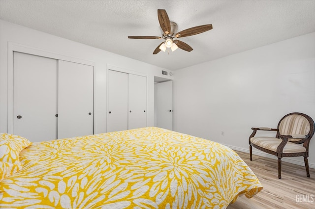 5600 Kirkside Dr Unit F, Bakersfield, CA 93311 - bedroom featuring light wood-style floors, two closets, baseboards, a textured ceiling, and a ceiling fan