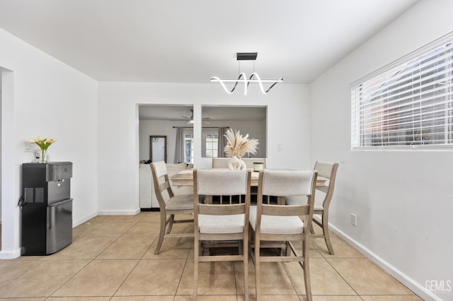 tiled dining space with a healthy amount of sunlight and ceiling fan with notable chandelier