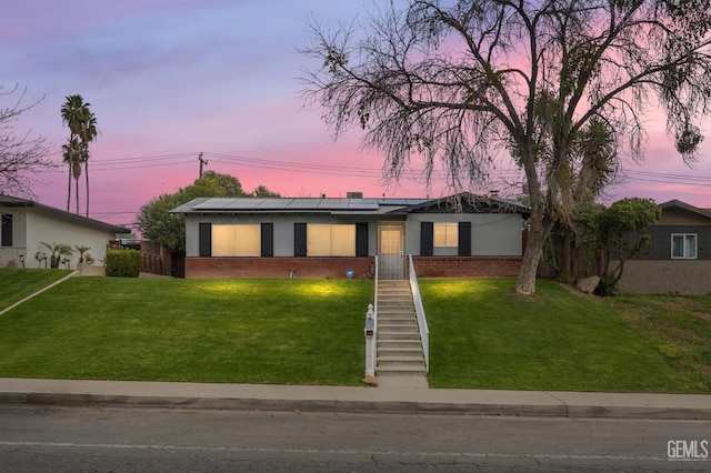 ranch-style house with a yard and solar panels