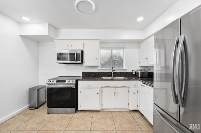 kitchen with white cabinetry, appliances with stainless steel finishes, sink, and dark stone counters