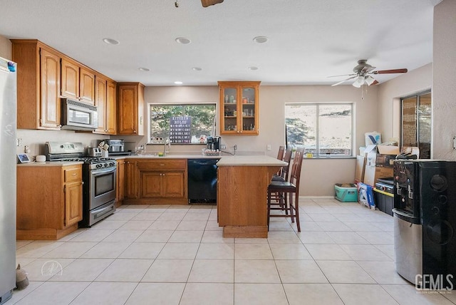 22381 William Tell Trl, Tehachapi, CA 93561 - kitchen with stainless steel gas range oven, black dishwasher, white microwave, a breakfast bar area, and brown cabinets