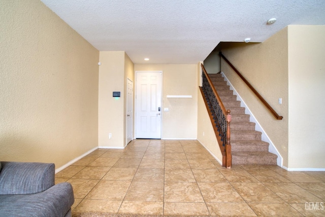 entryway with light tile patterned floors, a textured ceiling, baseboards, and stairs