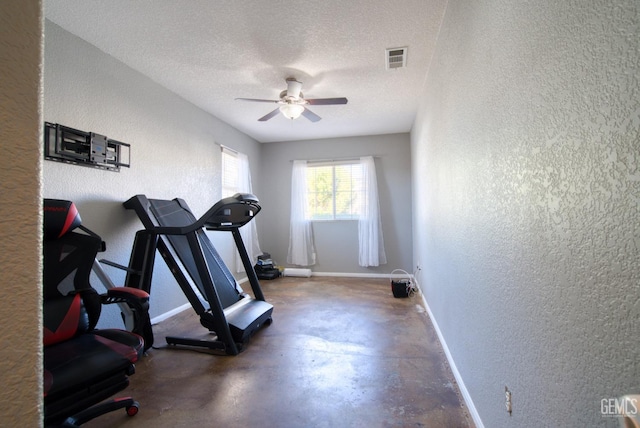 exercise area featuring baseboards, visible vents, a textured ceiling, and a textured wall