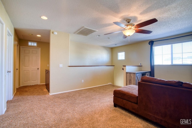 sitting room with baseboards, visible vents, light colored carpet, ceiling fan, and a textured ceiling