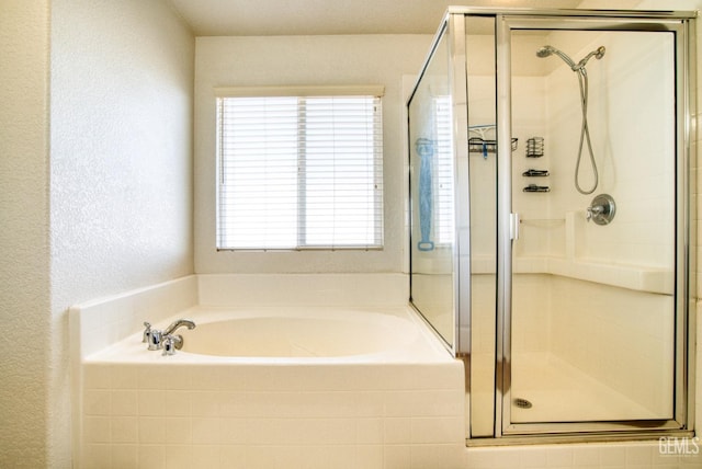 full bathroom featuring a stall shower, a garden tub, and a textured wall