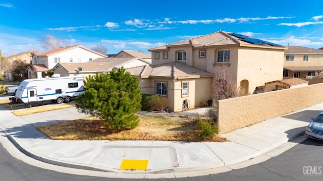 view of front of property with solar panels, a tiled roof, a residential view, and stucco siding