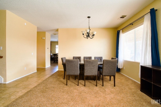 dining area featuring a textured ceiling, light tile patterned floors, visible vents, and a notable chandelier