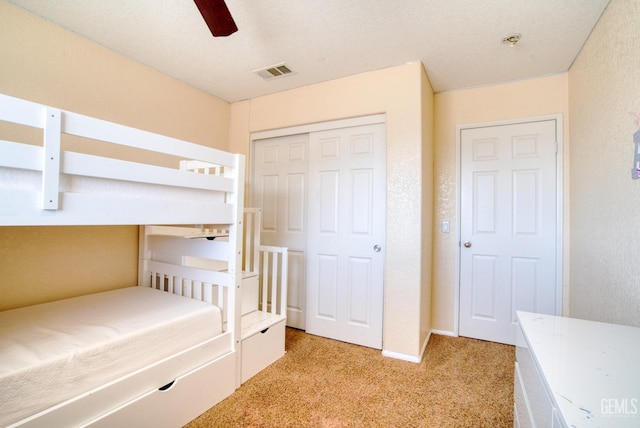 unfurnished bedroom featuring a ceiling fan, light colored carpet, a closet, and visible vents