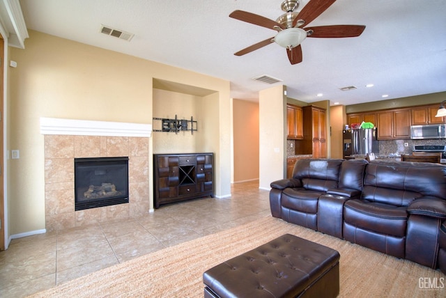 living area with a tile fireplace, visible vents, baseboards, and light tile patterned floors