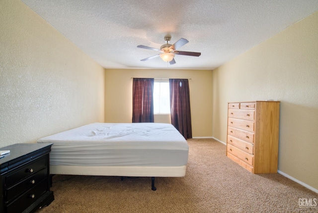 carpeted bedroom featuring a textured ceiling, a textured wall, ceiling fan, and baseboards