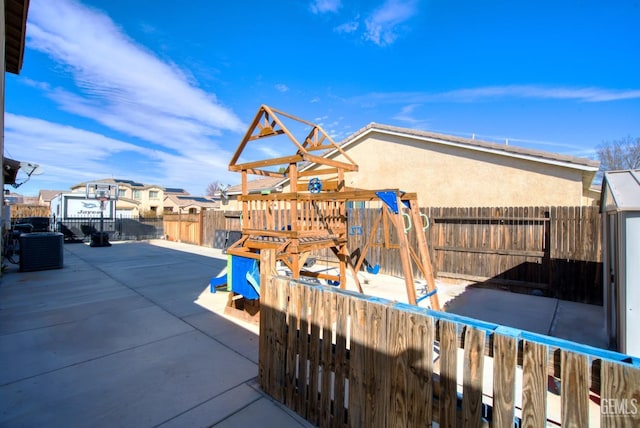 exterior space featuring central AC, a playground, and a fenced backyard