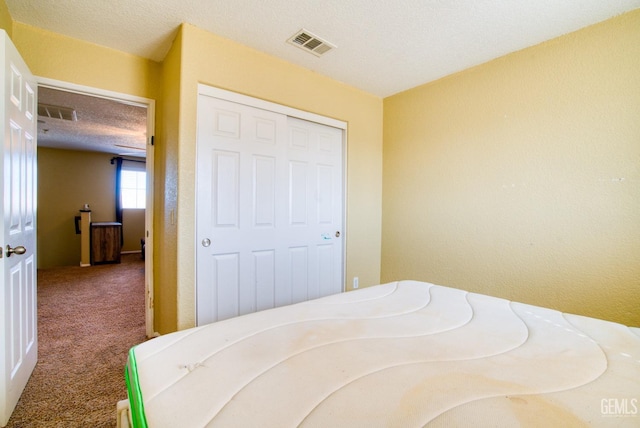 bedroom with carpet floors, a closet, visible vents, and a textured ceiling