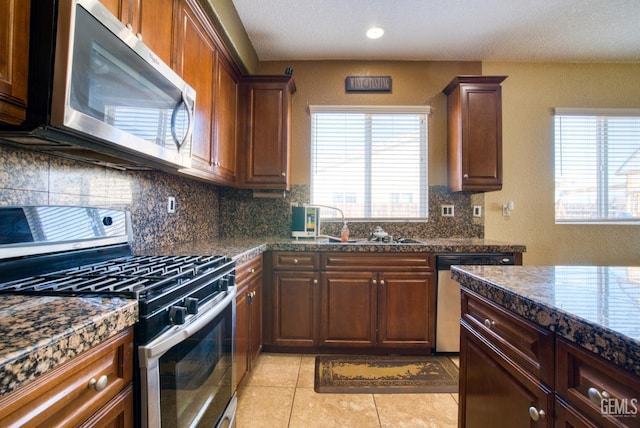 kitchen with light tile patterned floors, recessed lighting, a sink, appliances with stainless steel finishes, and backsplash