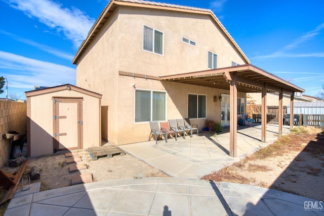 rear view of house with stucco siding, an outdoor structure, a fenced backyard, and a storage unit