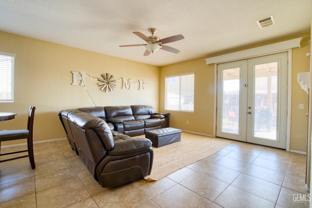 living room featuring light tile patterned floors, ceiling fan, a textured ceiling, visible vents, and french doors