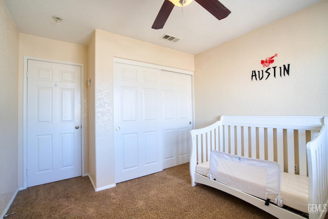 bedroom featuring visible vents, ceiling fan, carpet, a nursery area, and a closet