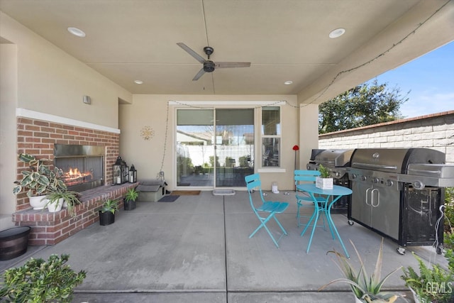 view of patio with grilling area, ceiling fan, and an outdoor brick fireplace