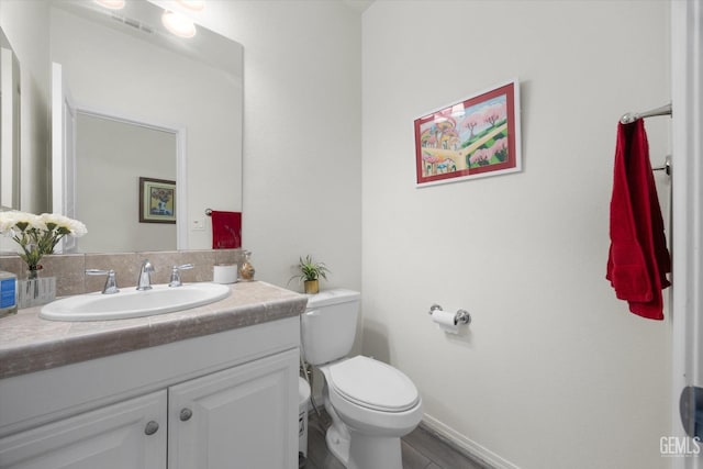 bathroom with baseboards, toilet, and vanity