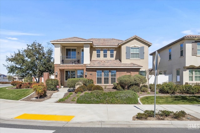 view of front of house featuring brick siding, stucco siding, and a balcony