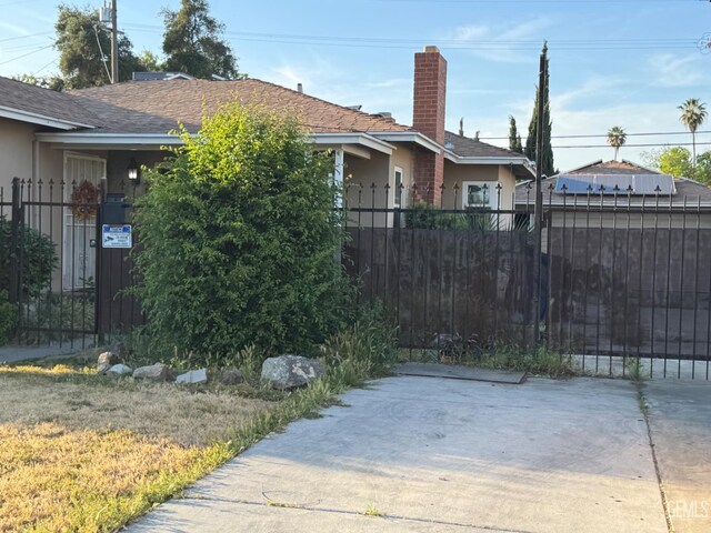 2625 E Michigan Ave, Fresno, CA 93703 - view of side of property featuring stucco siding, a chimney, a fenced front yard, and a shingled roof