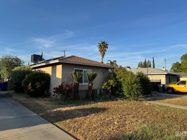 2625 E Michigan Ave, Fresno, CA 93703 - view of front of home featuring stucco siding, solar panels, and central AC