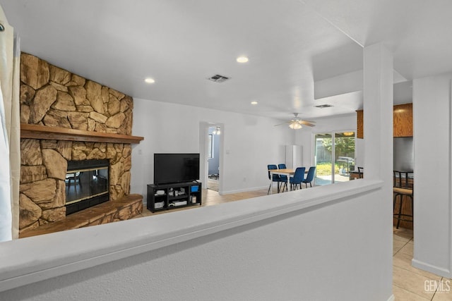 living room featuring a stone fireplace, a ceiling fan, recessed lighting, light tile patterned floors, and visible vents