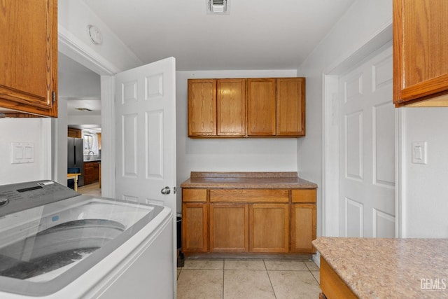 clothes washing area featuring cabinet space, visible vents, light tile patterned floors, and washer / dryer
